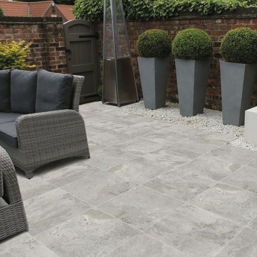 Image is showing a brick wall, patio wicker furniture, big Plant pots, and an Ottimo Oasis 16x32 Porcelain Pavers