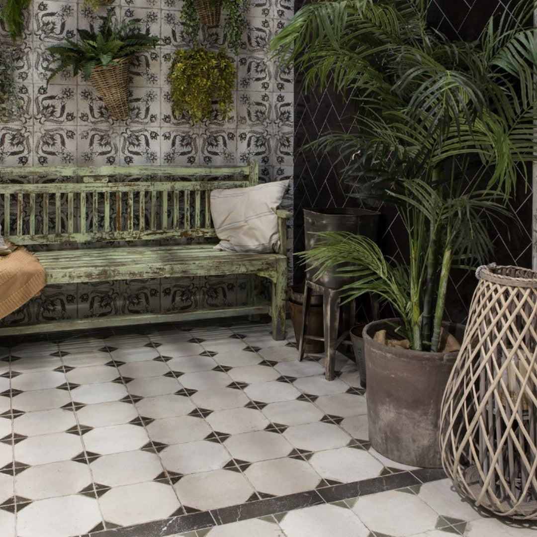 Ricket Pironda Black 18x18 Tile, Image is showing ricket tile at floors center, also a wooden bench with plant pots outside