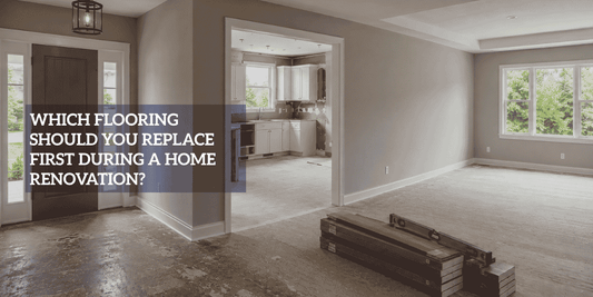 Home renovation showing worn entry flooring, unfinished kitchen, exposed living-room subfloor, flooring boxes, and level.