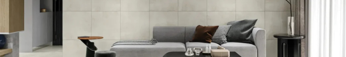 Image is showing a large format porcelain tiles installed in a living room, with sofas, table, a large size vase | Image also showing lighter color porcelain tiles installed